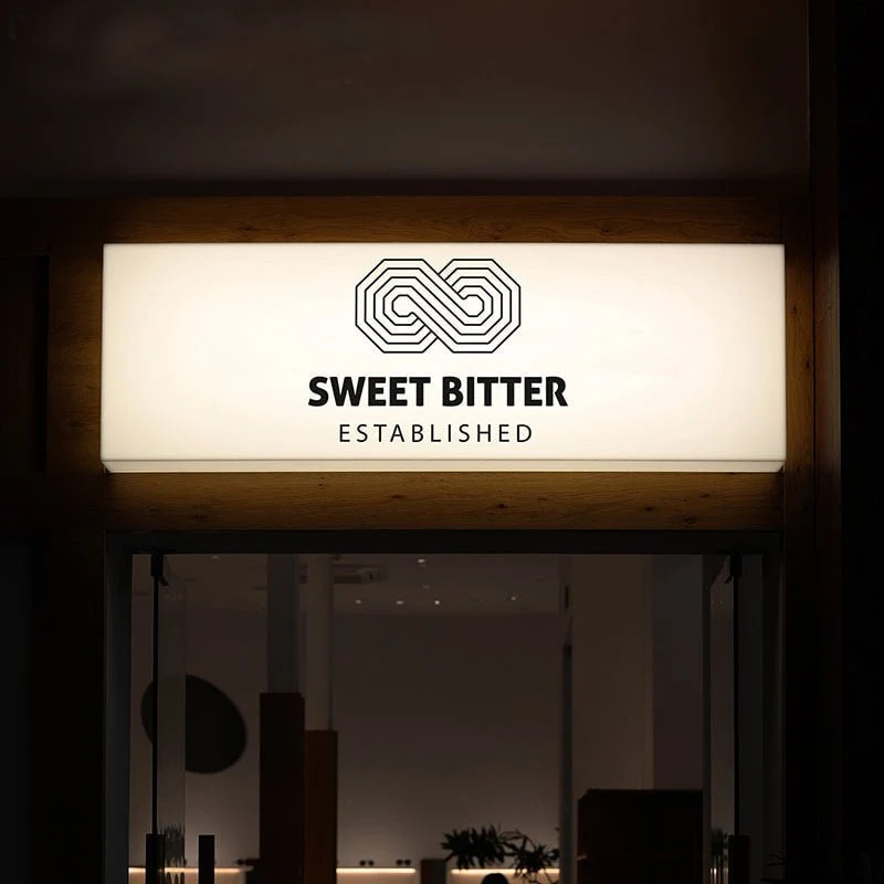 Face-lit lightbox cabinet sign glowing over a storefront entrance at night